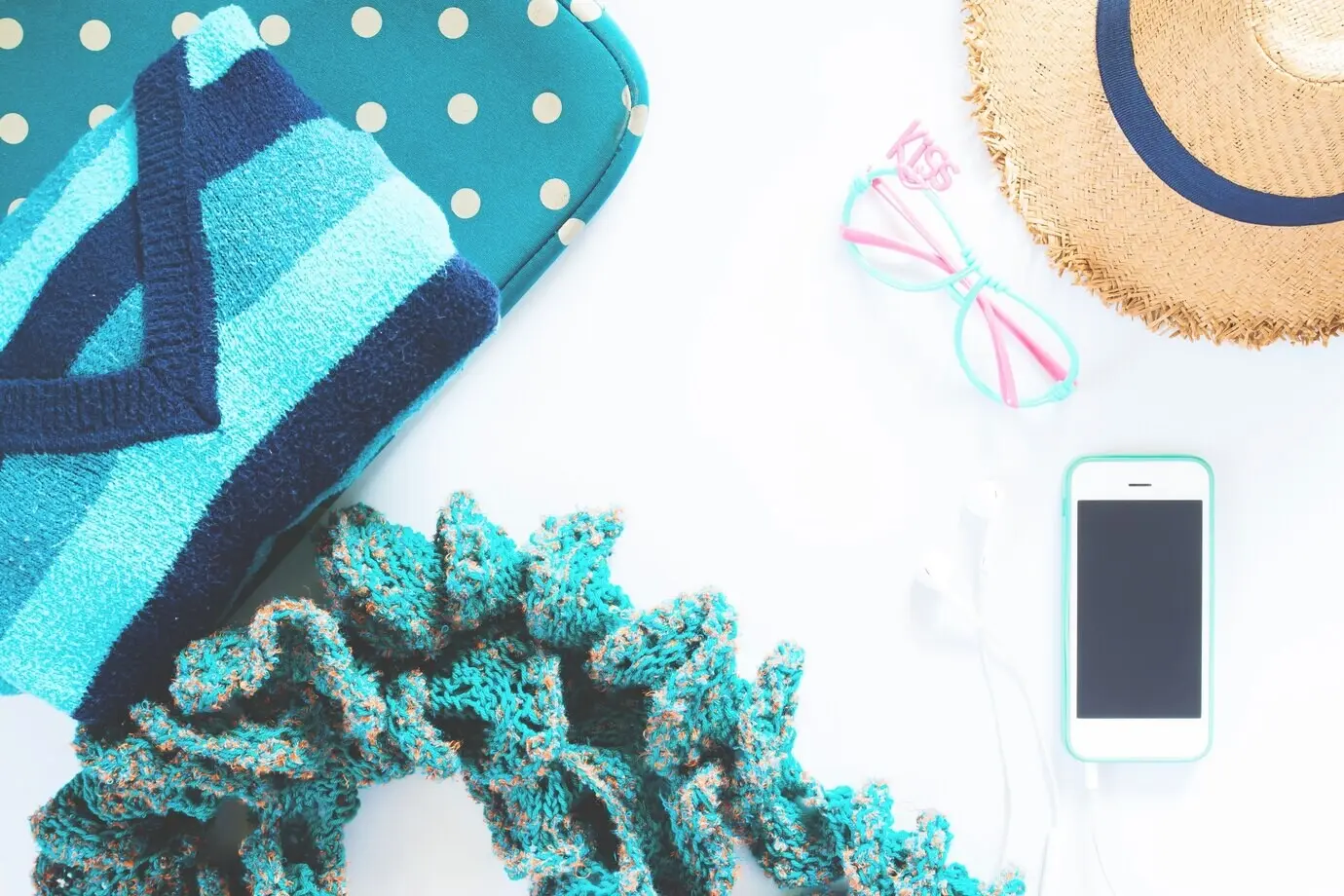 Флэт-лей коллаж женской одежды и аксессуаров: футболка, модные очки, шляпа, мобильный телефон и наушник на белом фоне. Концепция зелёного цвета.